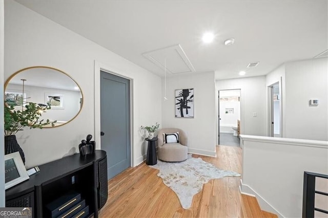 interior space with visible vents, light wood-type flooring, attic access, and baseboards