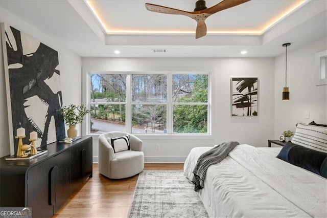 bedroom featuring visible vents, a tray ceiling, wood finished floors, and recessed lighting