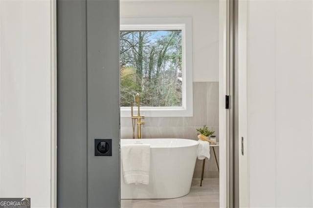 bathroom with a soaking tub and tile walls