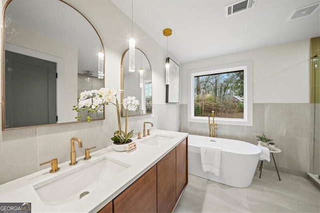 full bath with a freestanding tub, visible vents, and a sink