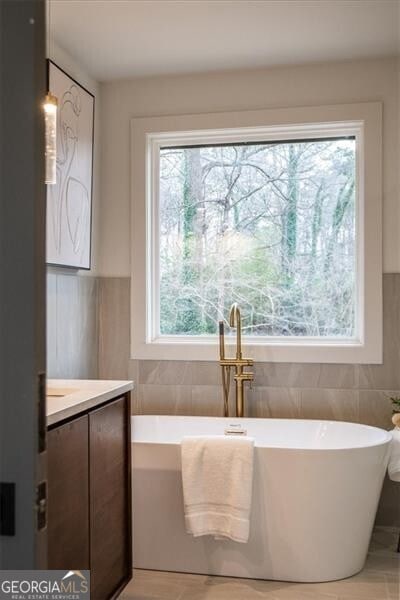 full bathroom with a freestanding tub and tile walls