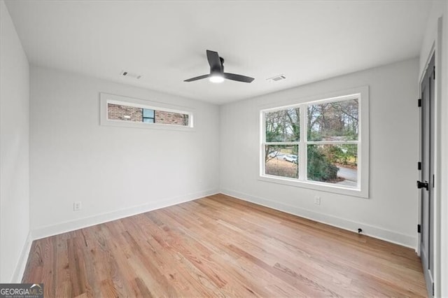 empty room featuring a wealth of natural light, baseboards, visible vents, and light wood finished floors