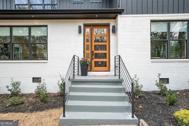 entrance to property featuring brick siding, crawl space, and board and batten siding