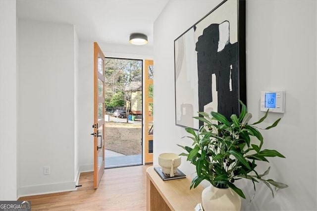 doorway with light wood-style flooring and baseboards