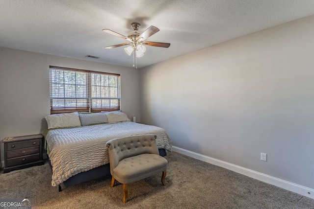 bedroom with ceiling fan, carpet floors, and a textured ceiling