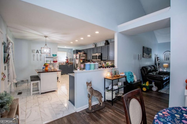 kitchen featuring gray cabinets, decorative light fixtures, a kitchen breakfast bar, kitchen peninsula, and stainless steel appliances