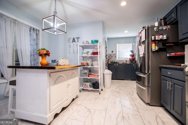 kitchen with pendant lighting, tasteful backsplash, a breakfast bar area, wooden counters, and stainless steel fridge