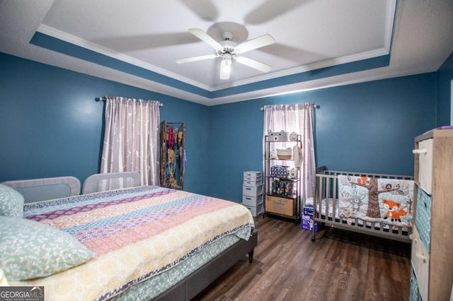 bedroom with a tray ceiling, dark wood-type flooring, and ornamental molding