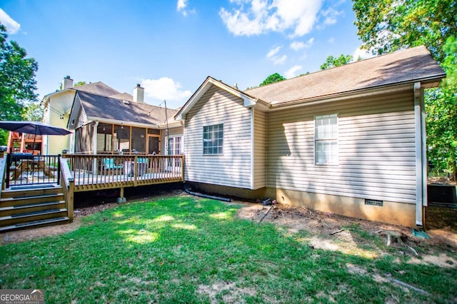 rear view of house with a yard, a sunroom, and a deck