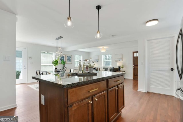 kitchen with dark stone countertops, decorative light fixtures, wood-type flooring, and a center island