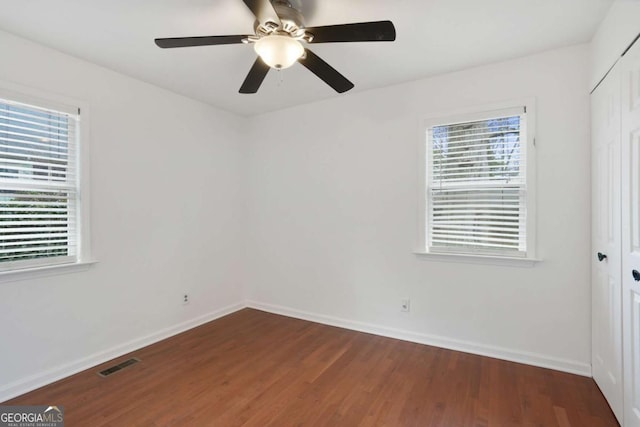 unfurnished room with a healthy amount of sunlight, dark wood-type flooring, and ceiling fan