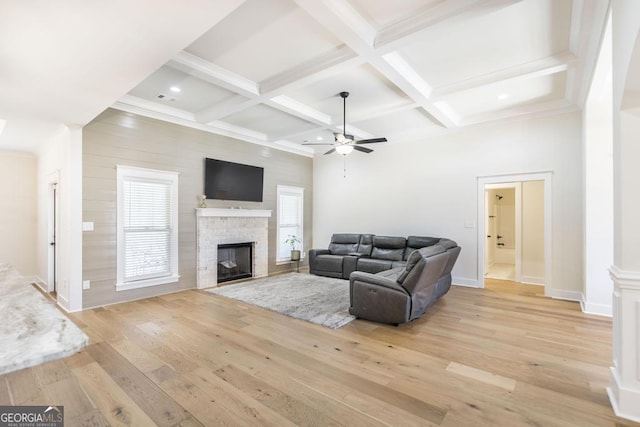 living area with light wood-style flooring, coffered ceiling, a ceiling fan, a brick fireplace, and beam ceiling