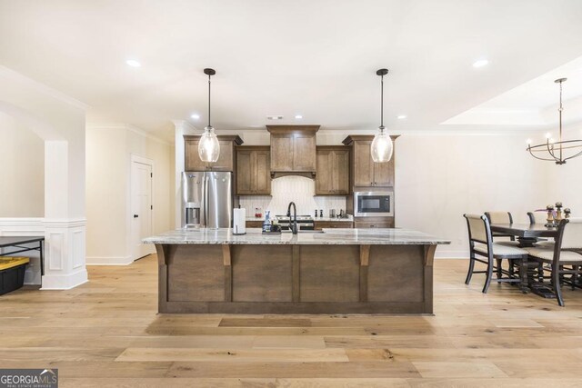 kitchen with premium range hood, appliances with stainless steel finishes, tasteful backsplash, and light hardwood / wood-style flooring