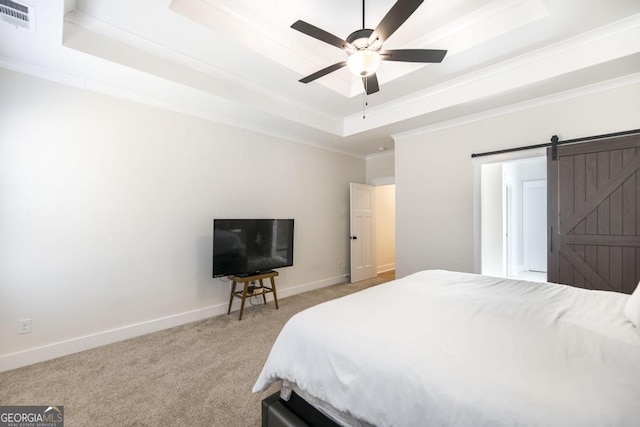 bedroom with a barn door, light carpet, visible vents, baseboards, and a tray ceiling