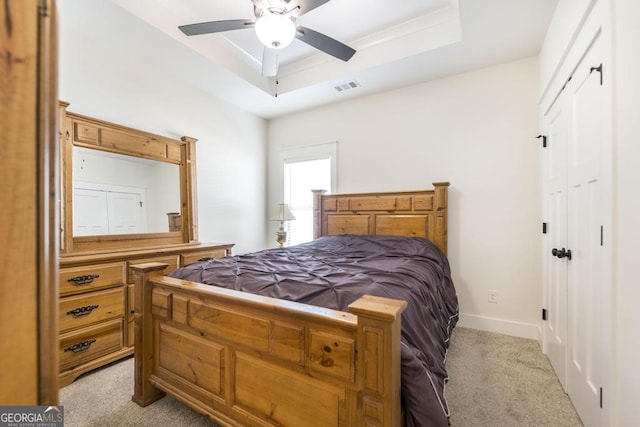 bedroom featuring a raised ceiling, light colored carpet, visible vents, ceiling fan, and baseboards