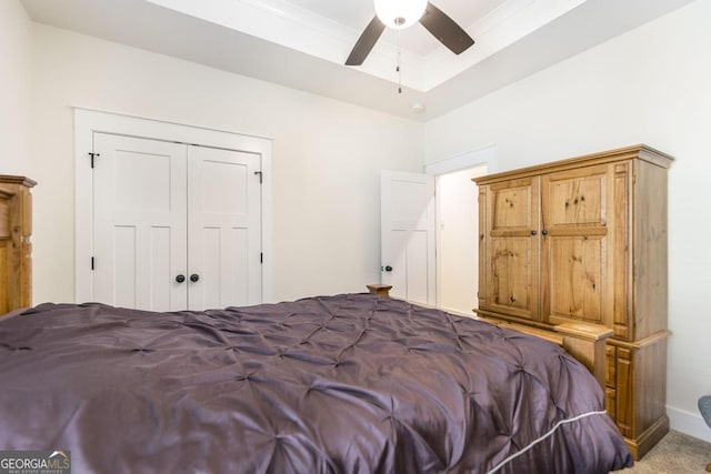 bedroom featuring ceiling fan, carpet floors, a tray ceiling, and a closet