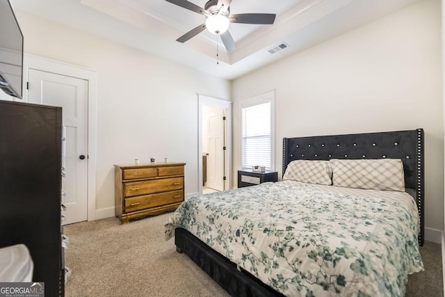 bedroom featuring carpet flooring, a ceiling fan, visible vents, baseboards, and a tray ceiling