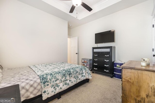 carpeted bedroom featuring ceiling fan and a tray ceiling