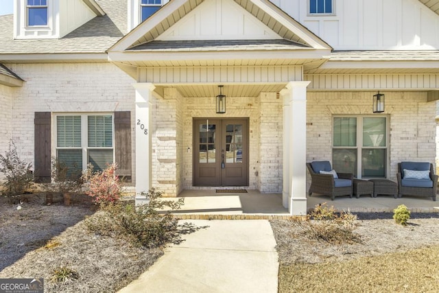 property entrance with french doors, brick siding, roof with shingles, a porch, and board and batten siding