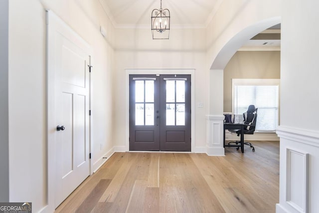 foyer with french doors, light wood-style flooring, a wealth of natural light, and crown molding