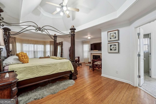 bedroom featuring ceiling fan, a tray ceiling, wood-type flooring, ornamental molding, and vaulted ceiling