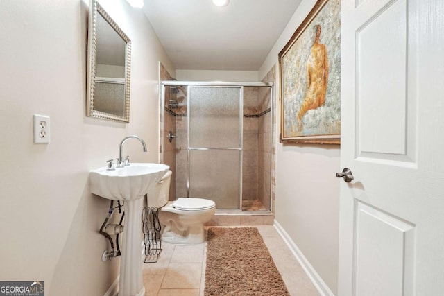 bathroom with tile patterned floors, toilet, and a shower with door