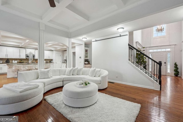 living room with hardwood / wood-style flooring, a barn door, coffered ceiling, and beamed ceiling