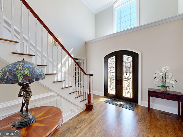 foyer with arched walkways, french doors, plenty of natural light, and wood finished floors