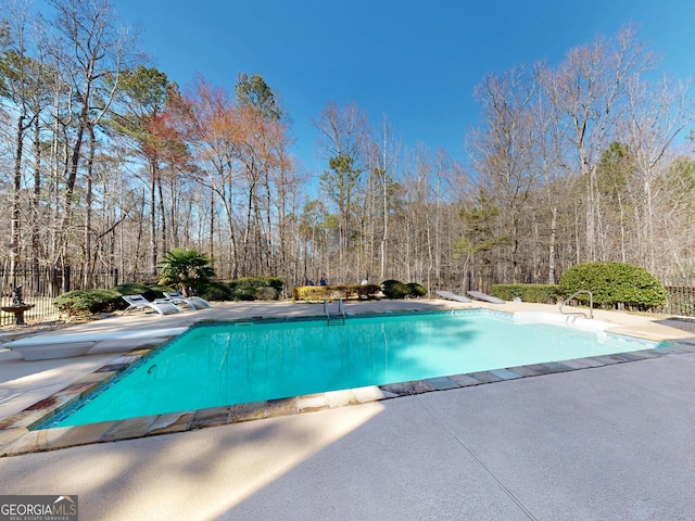 outdoor pool with a diving board, a patio, and fence