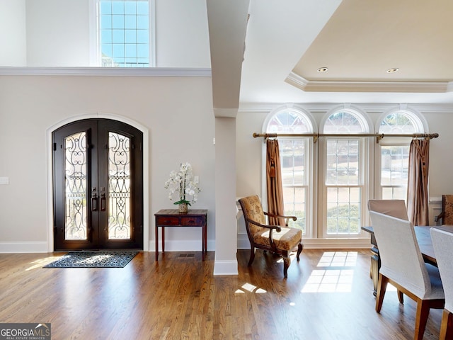 foyer entrance with arched walkways, french doors, wood finished floors, and baseboards