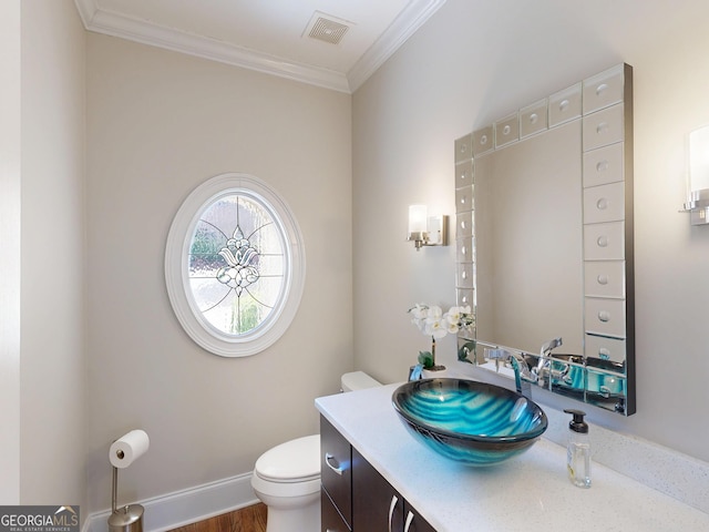 half bath with baseboards, visible vents, toilet, ornamental molding, and vanity