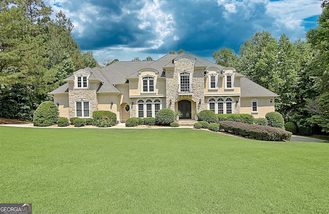 french country inspired facade with stone siding, a front lawn, and stucco siding