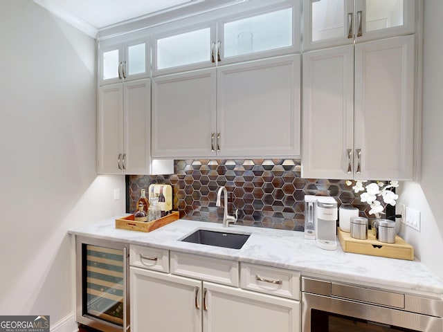 kitchen featuring tasteful backsplash, wine cooler, a sink, and white cabinets