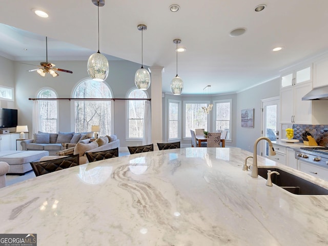 kitchen featuring glass insert cabinets, white cabinetry, a sink, and decorative light fixtures