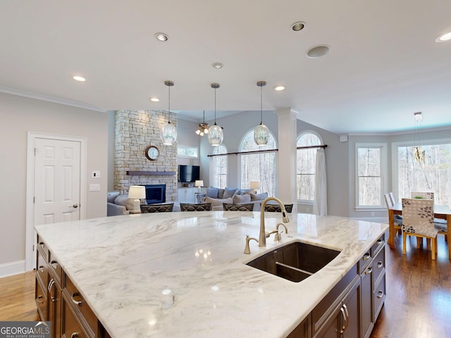 kitchen featuring decorative light fixtures, light stone counters, a sink, and wood finished floors