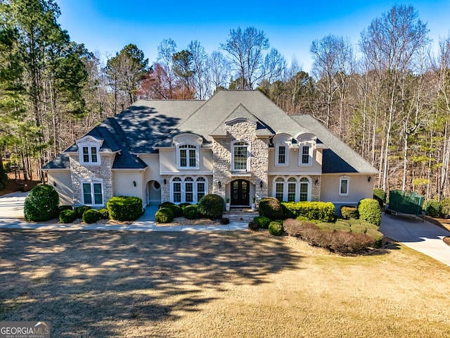 french country home featuring stone siding and stucco siding