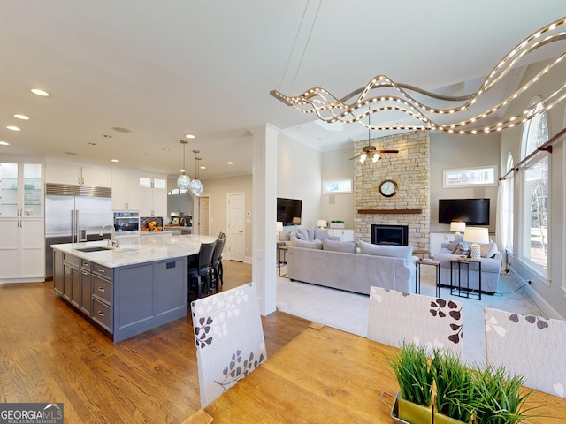 interior space featuring crown molding, recessed lighting, ceiling fan, a stone fireplace, and wood finished floors