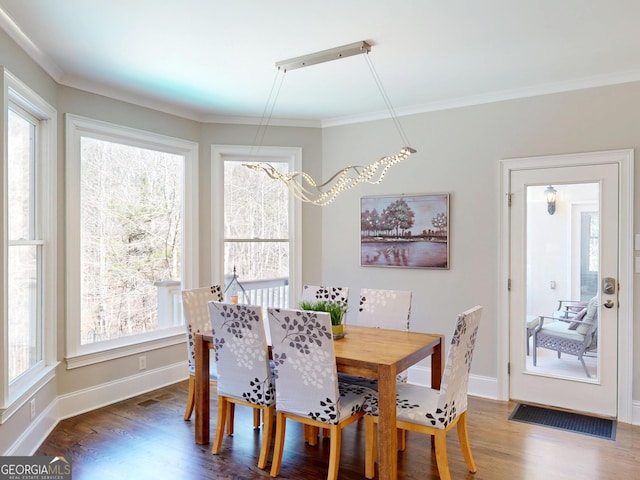 dining room with wood finished floors, a wealth of natural light, and crown molding