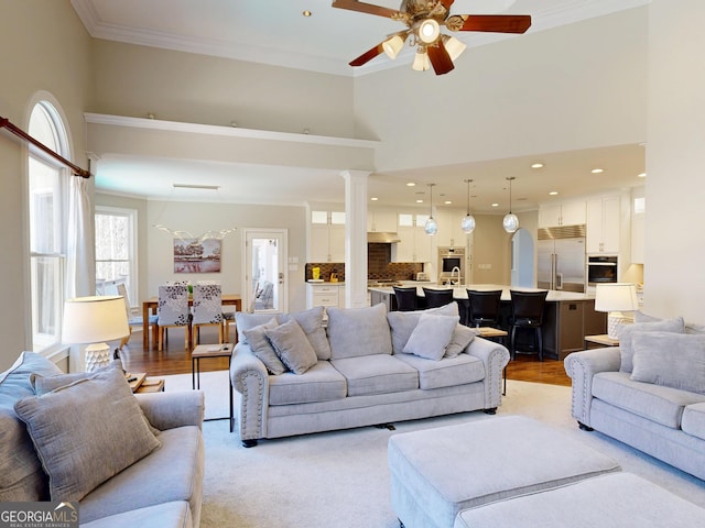 living room featuring recessed lighting, a high ceiling, a ceiling fan, ornamental molding, and ornate columns