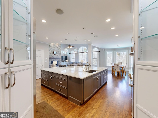 kitchen with dark brown cabinets, open floor plan, a sink, and wood finished floors