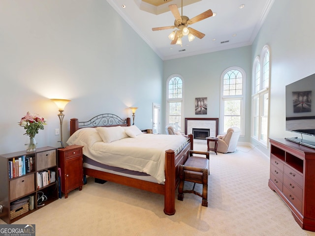 bedroom featuring ornamental molding, a fireplace, a towering ceiling, and light colored carpet