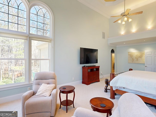 carpeted bedroom with baseboards, visible vents, arched walkways, a towering ceiling, and crown molding