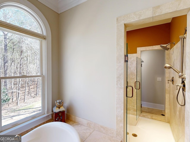 full bath with baseboards, a tub, tile patterned floors, crown molding, and a shower stall