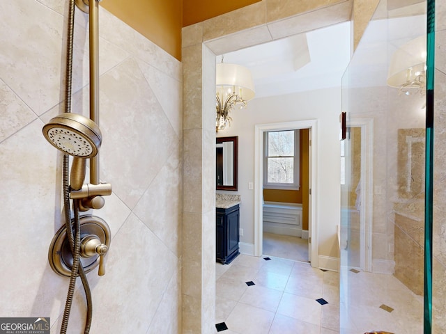 full bathroom featuring vanity, baseboards, tiled shower, tile patterned floors, and an inviting chandelier