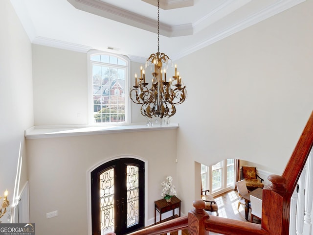 entrance foyer featuring arched walkways, french doors, a raised ceiling, and crown molding