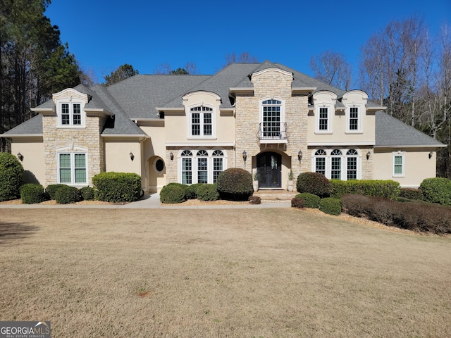 french provincial home featuring stone siding and a front lawn