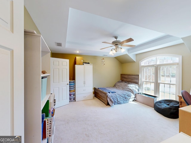 bedroom with ceiling fan, visible vents, a raised ceiling, and light colored carpet