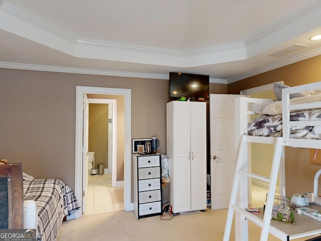 bedroom with ornamental molding, a raised ceiling, light colored carpet, and ensuite bath