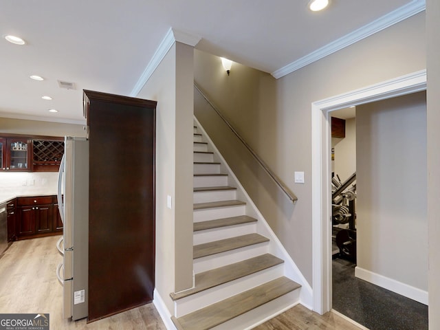 staircase featuring recessed lighting, visible vents, ornamental molding, wood finished floors, and baseboards