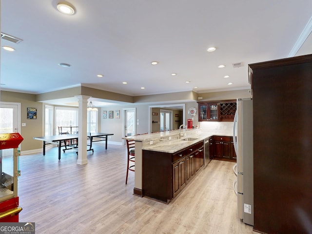 kitchen with a sink, visible vents, appliances with stainless steel finishes, a kitchen bar, and ornate columns